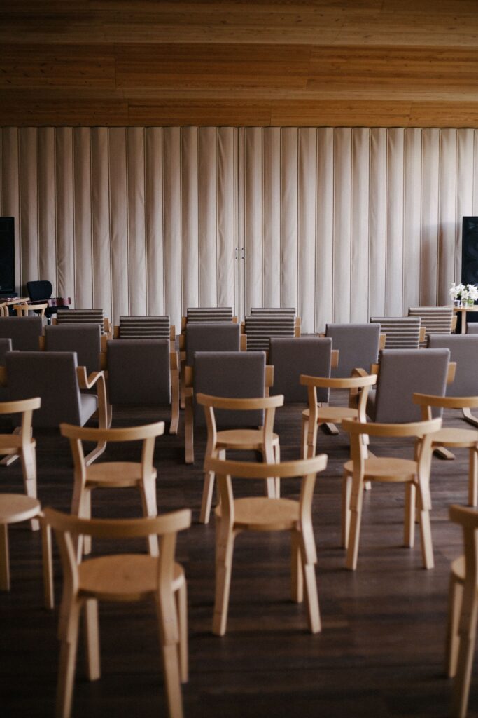 Empty modern auditorium with wooden chairs and stage setup, ideal for events.